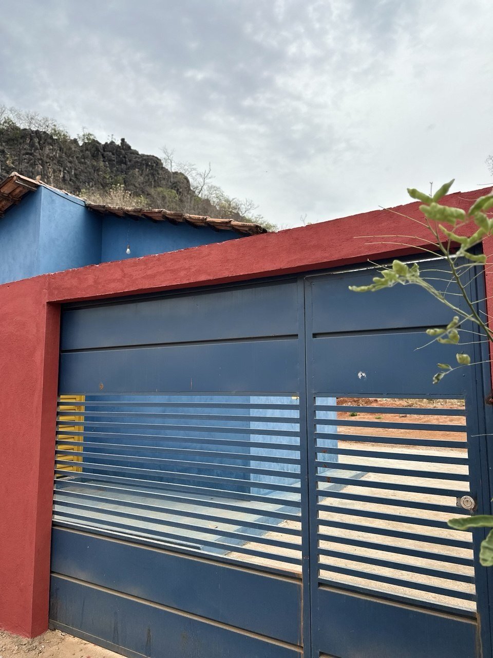 Portão e muro do chalé, com o morro ao fundo
